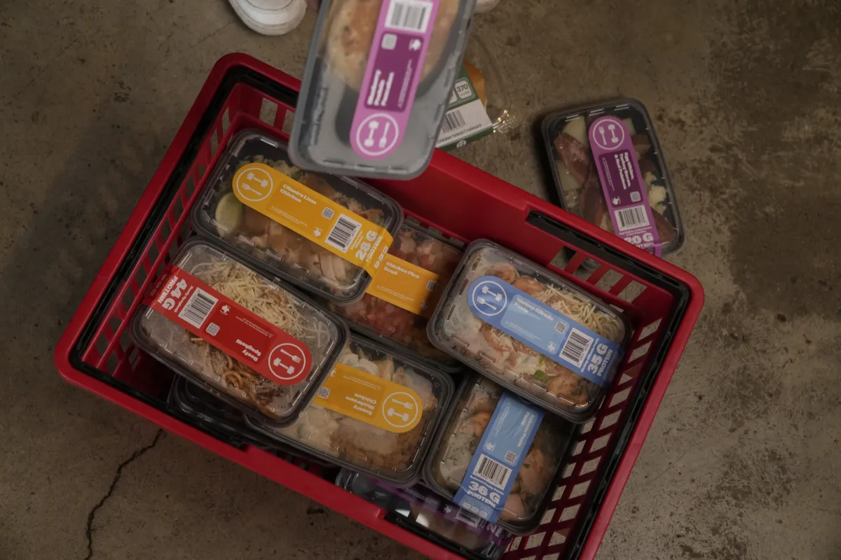 A red Fork to Fit shopping basket filled with labeled meals in rectangular containers